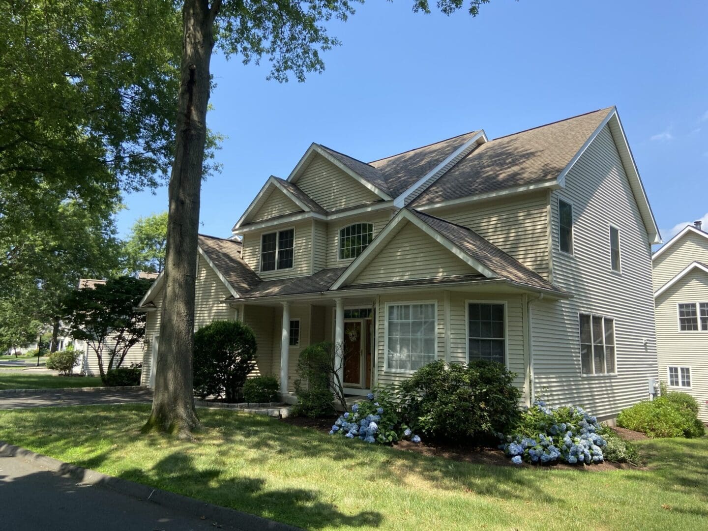 Two-story beige house with green lawn.