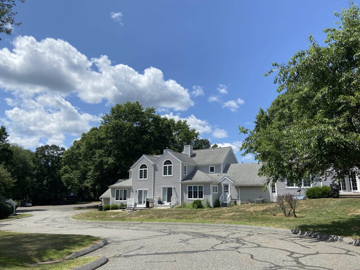 Gray house with trees and driveway.