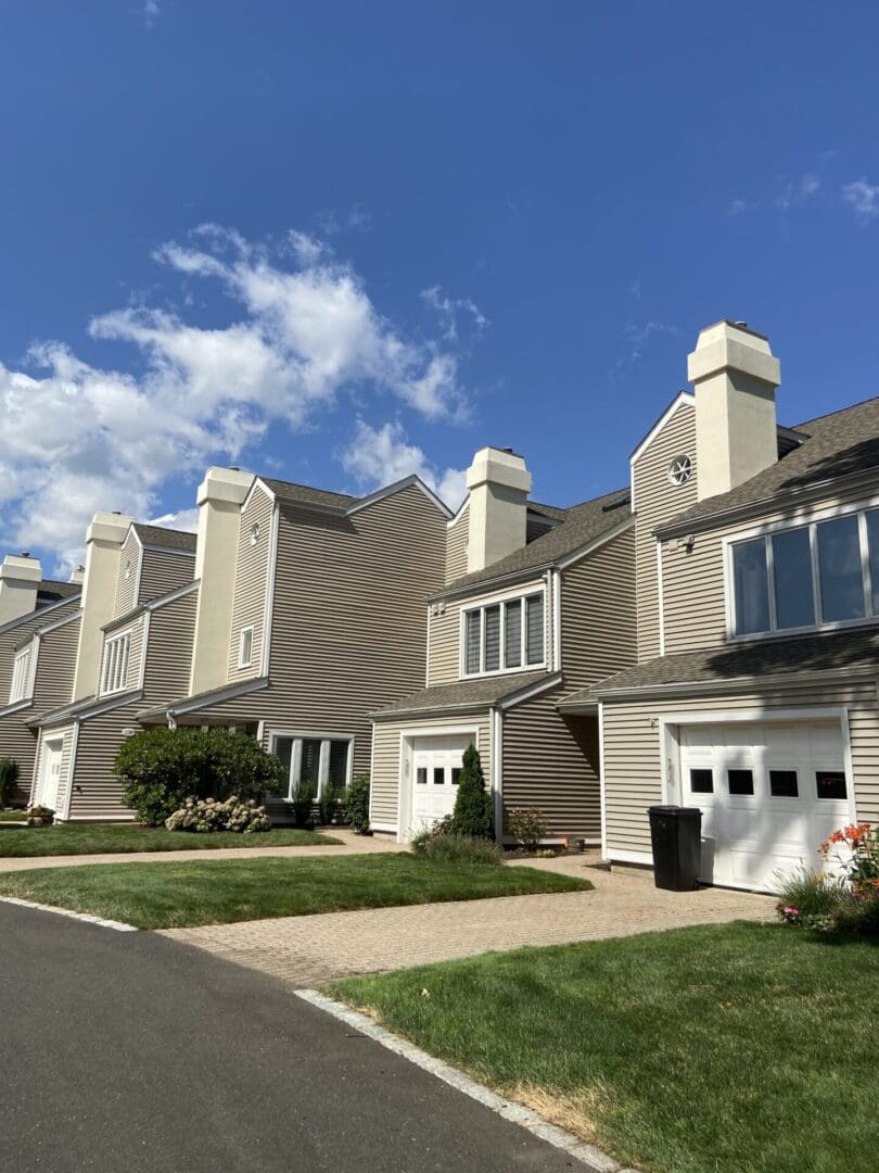 Row of beige townhouses with green lawns.