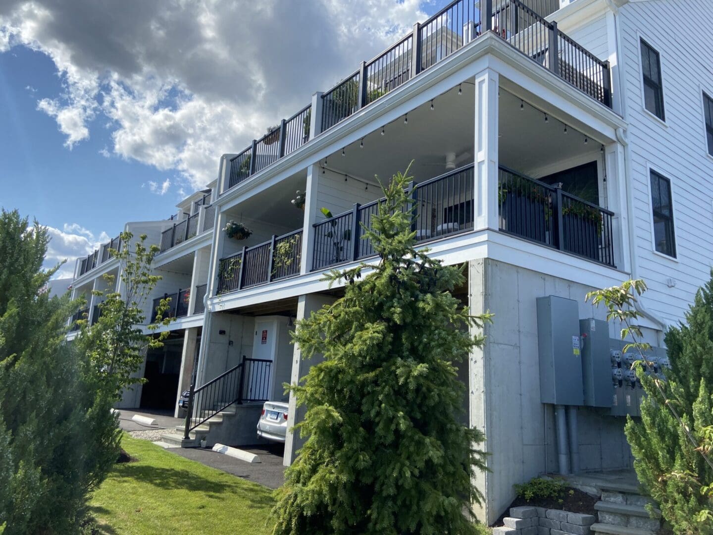 White building with balconies and green trees.