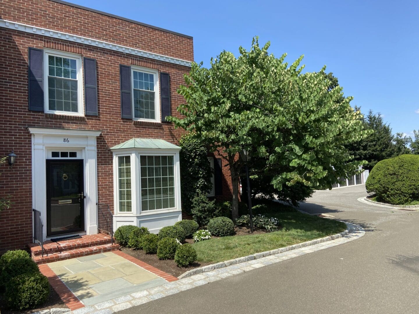 Brick house with black door and green tree.