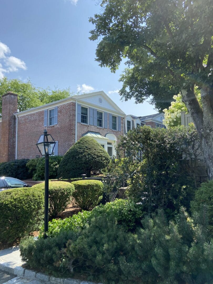 Brick house with green bushes and a lamppost.