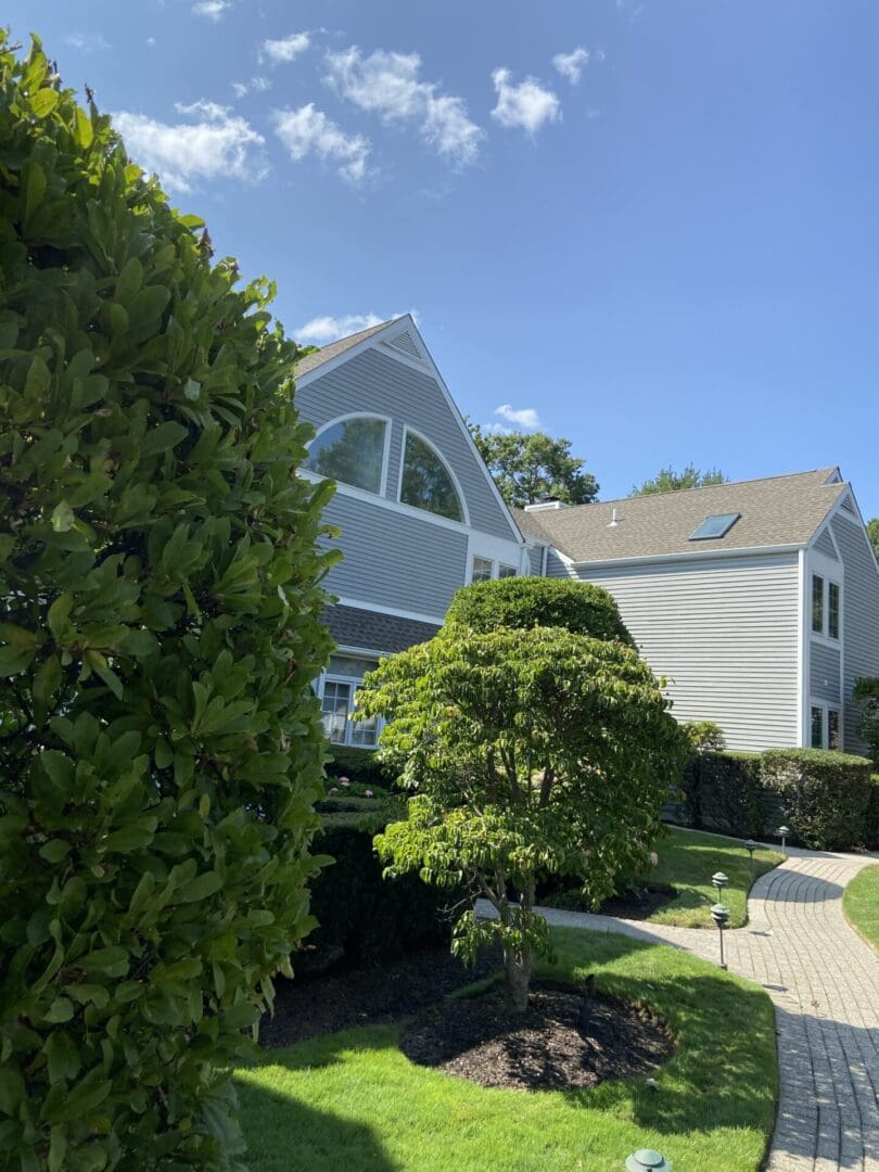 Gray house with green bushes and walkway.