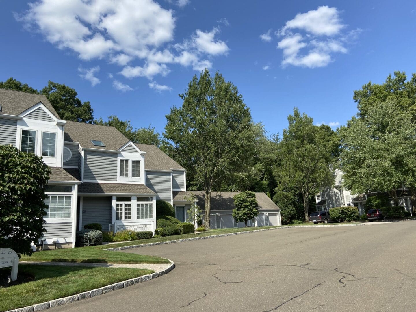 Gray townhouse with a driveway and green lawn.