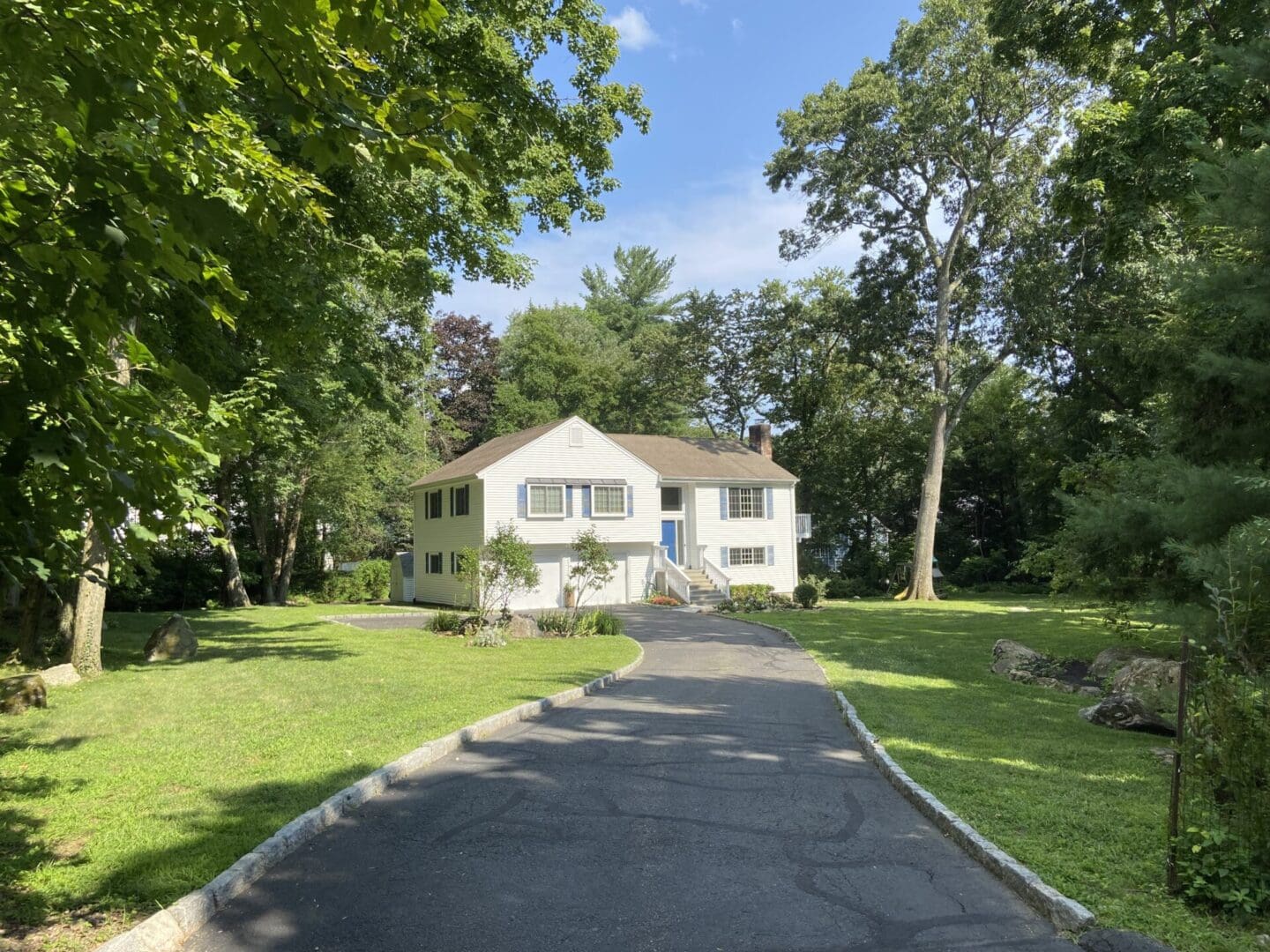 White house with driveway and green lawn.