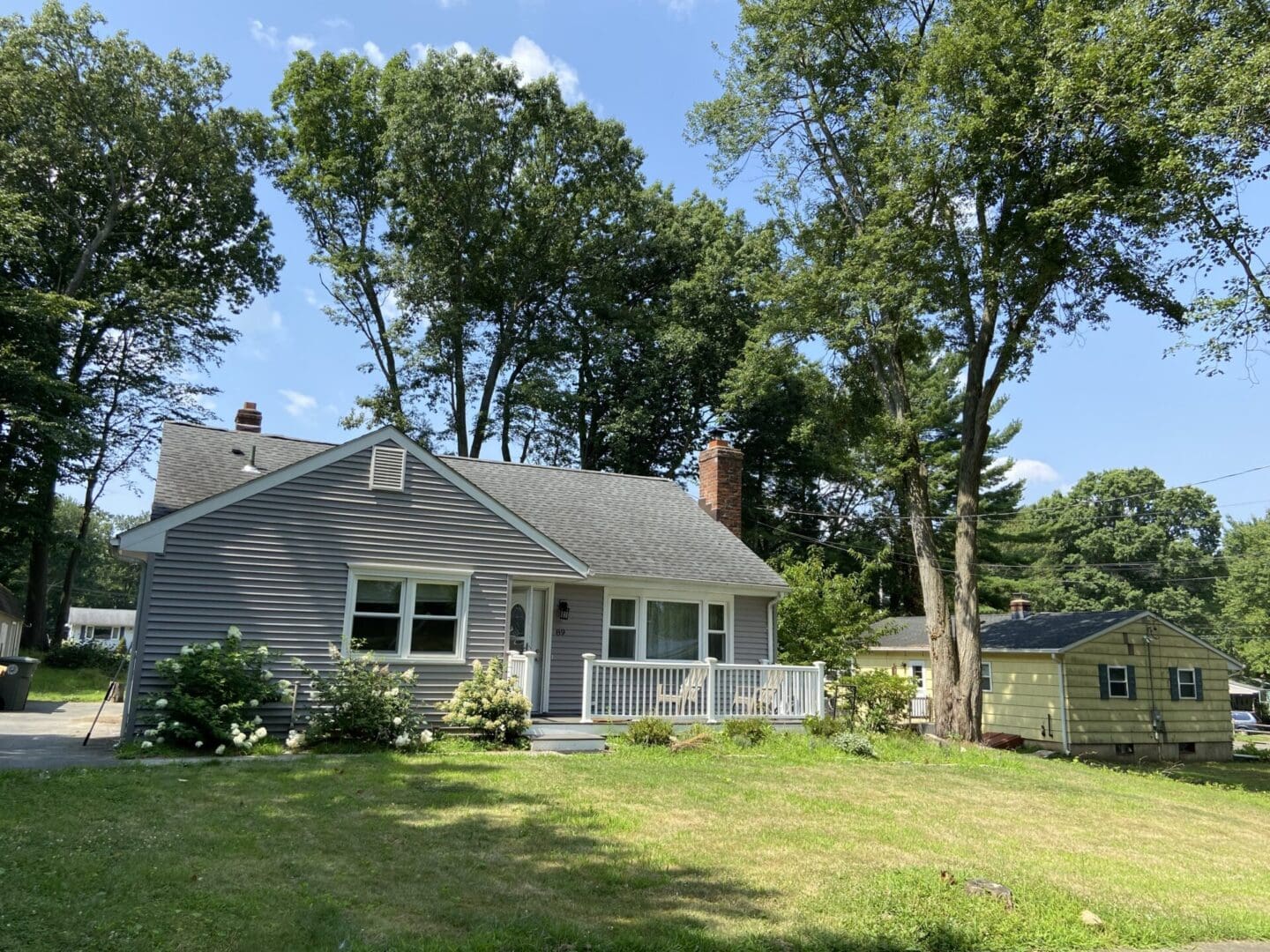 Gray house with green lawn and trees.