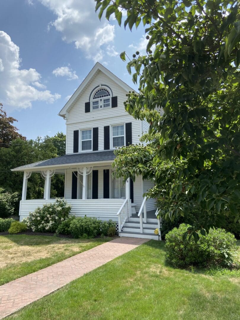 White house with porch and front yard.