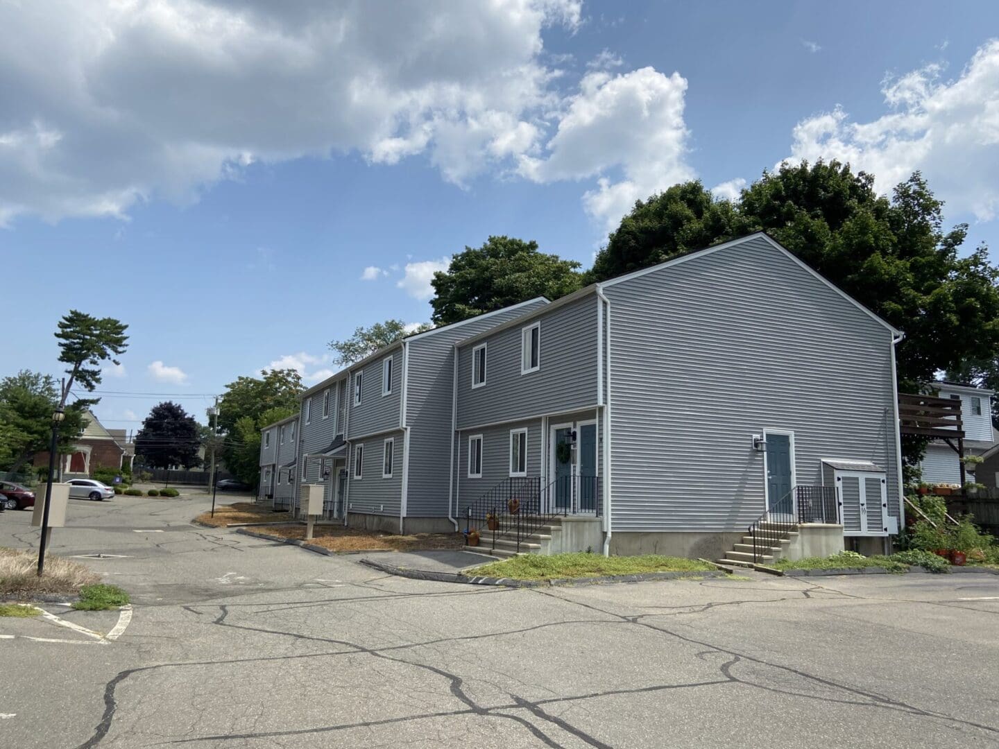 Gray apartment building with parking lot.