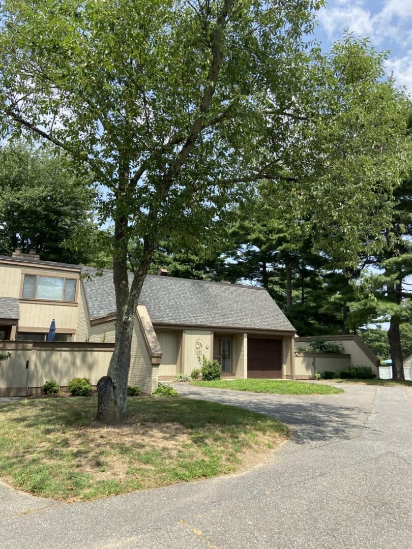 A gray house with a green lawn and trees.