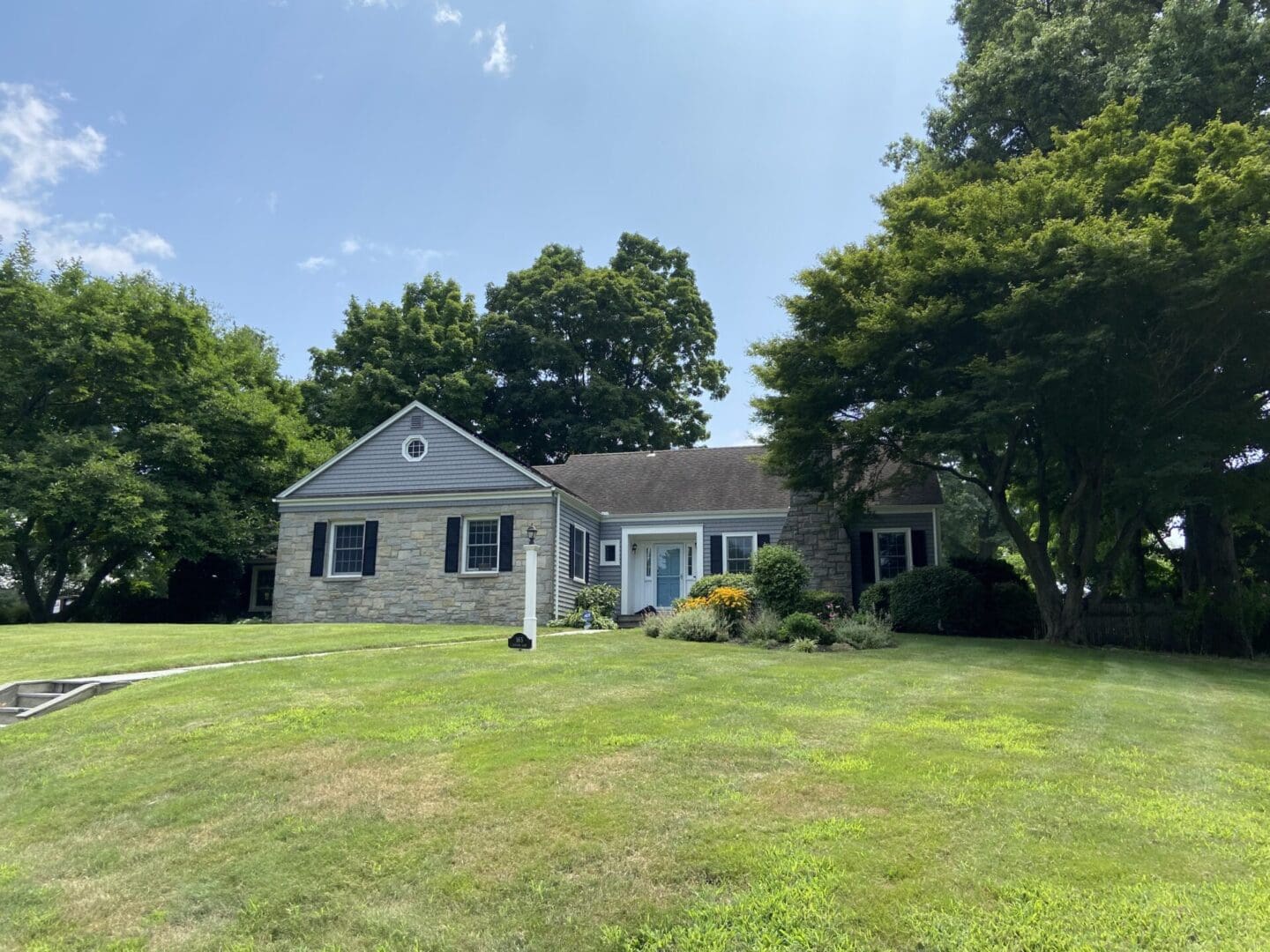 Stone house with blue door on lawn.