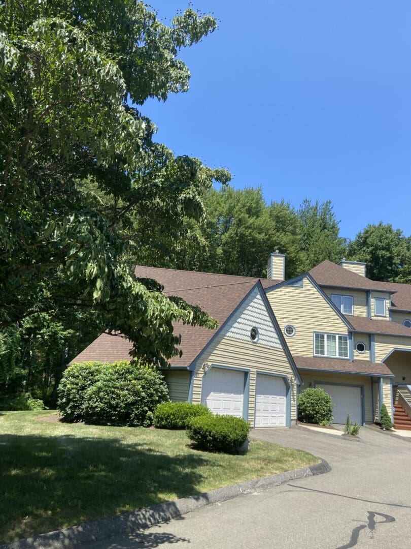 Tan house with attached garages and trees.