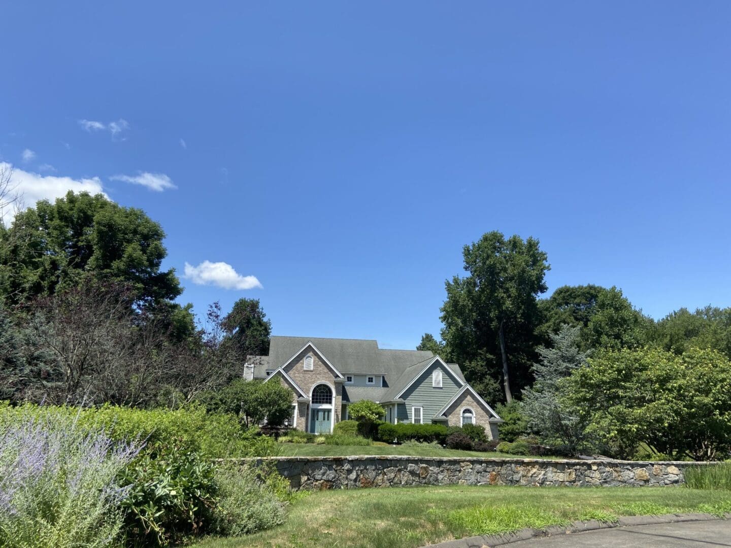 Stone wall with green house and trees.