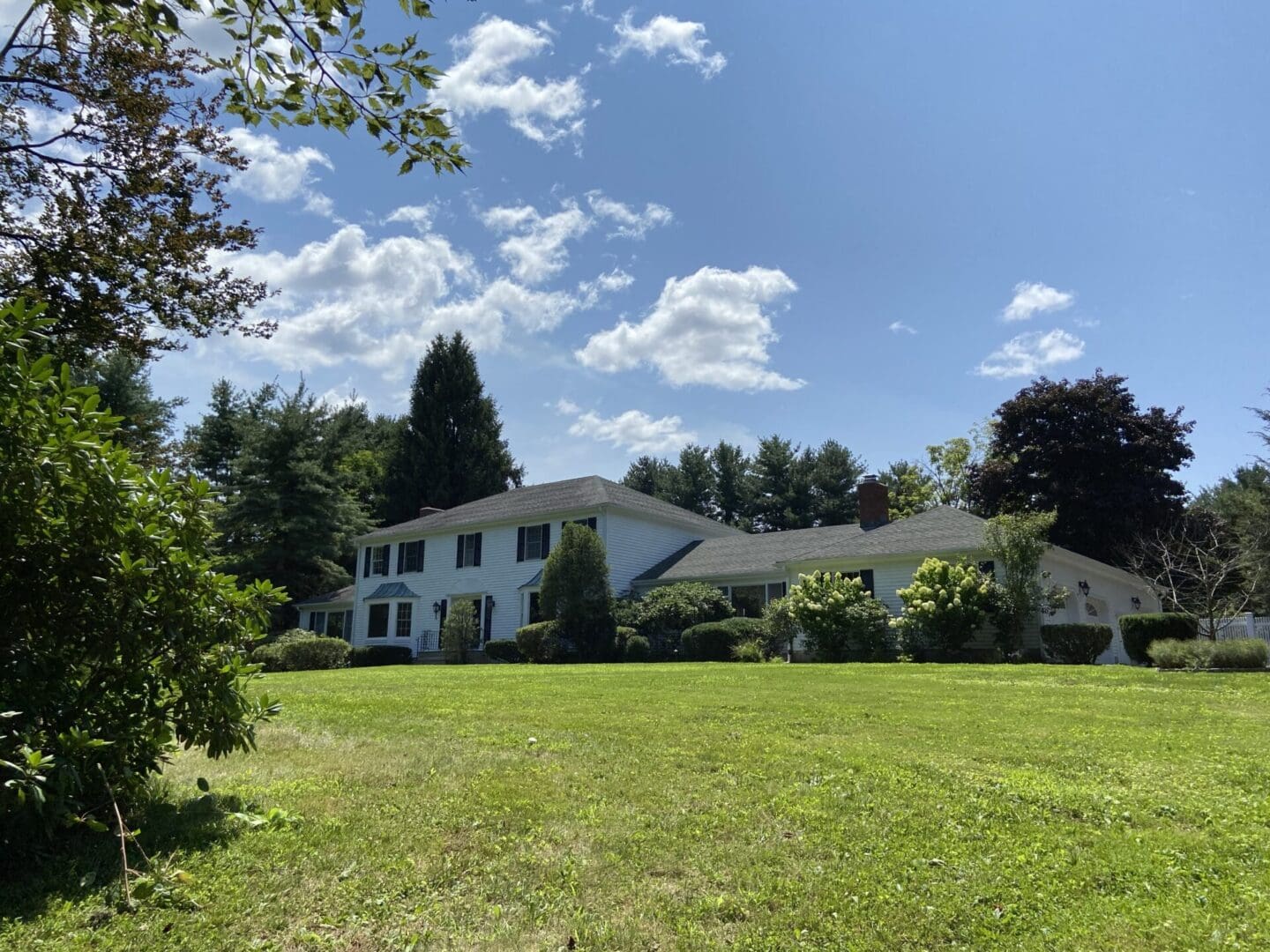 White house with green lawn and trees.