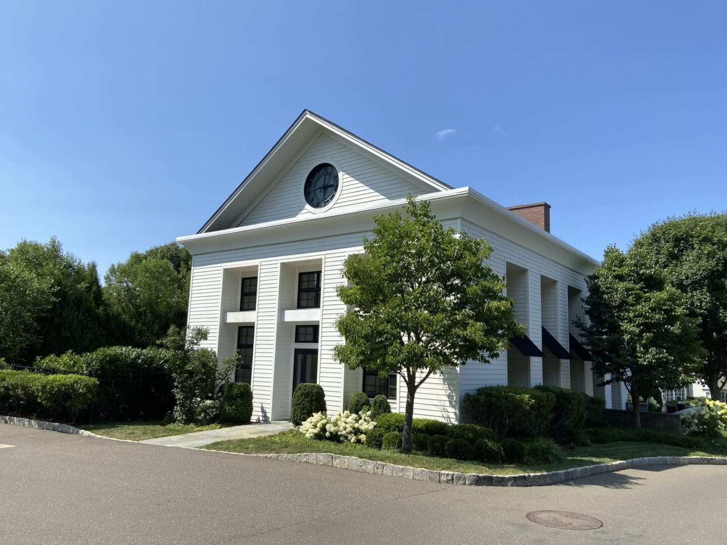 White building with clock and trees.