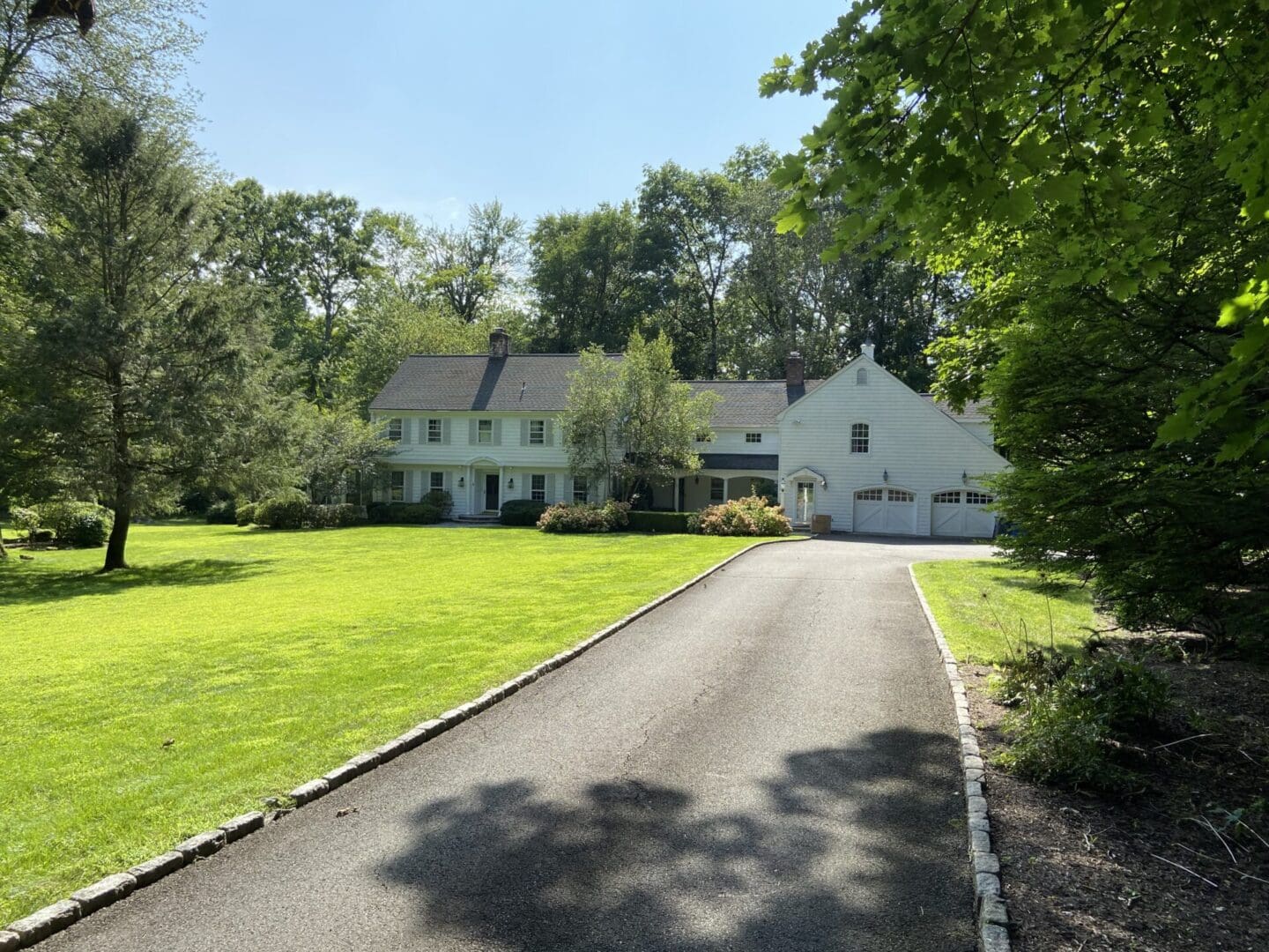 White house with driveway and green lawn.