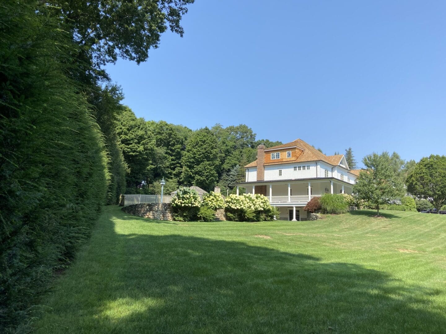 White house with porch and green lawn.