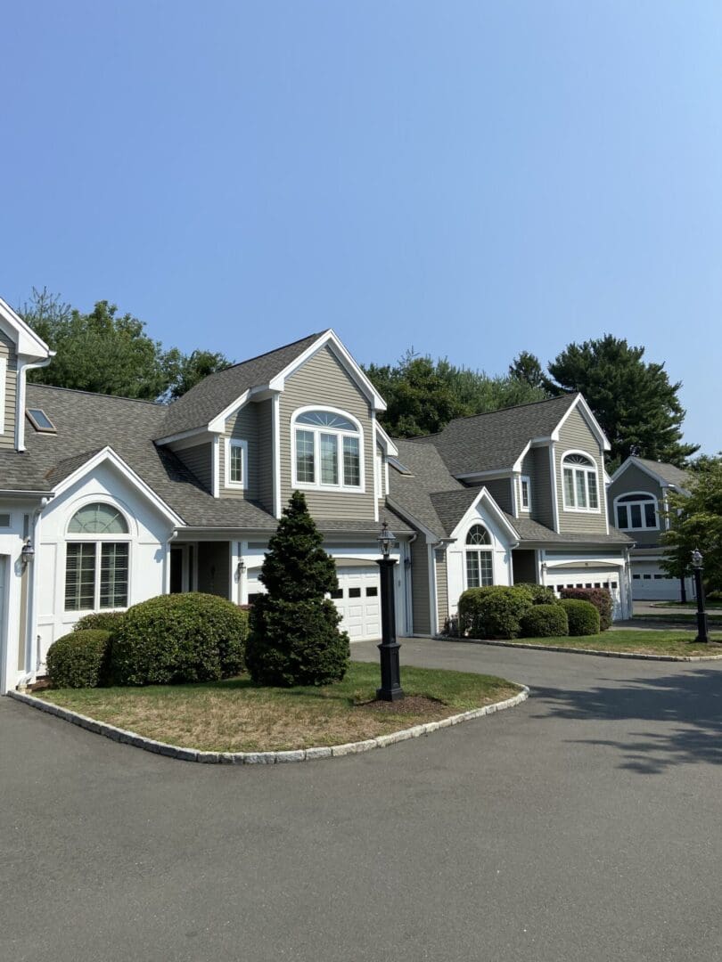 Gray townhouses with a driveway and shrubs.