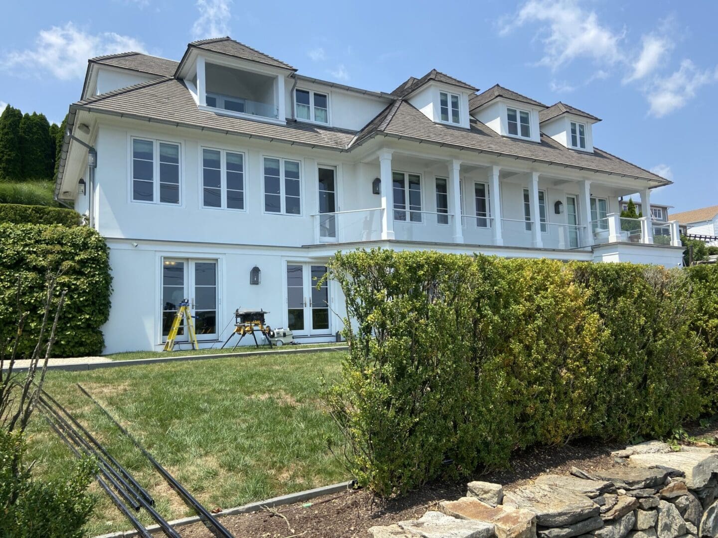 White house with large windows and a hedge.