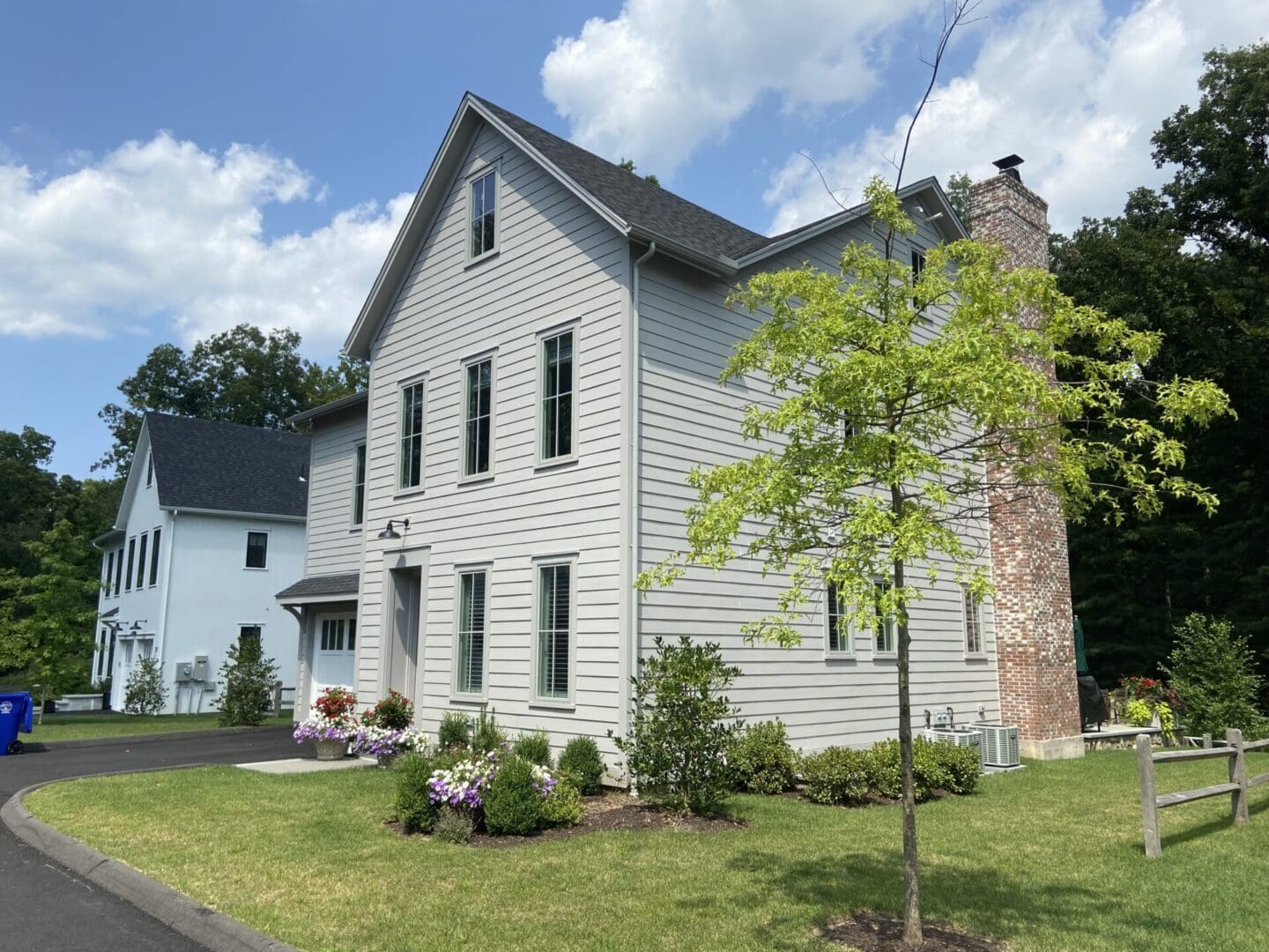 Gray house with brick chimney and tree.