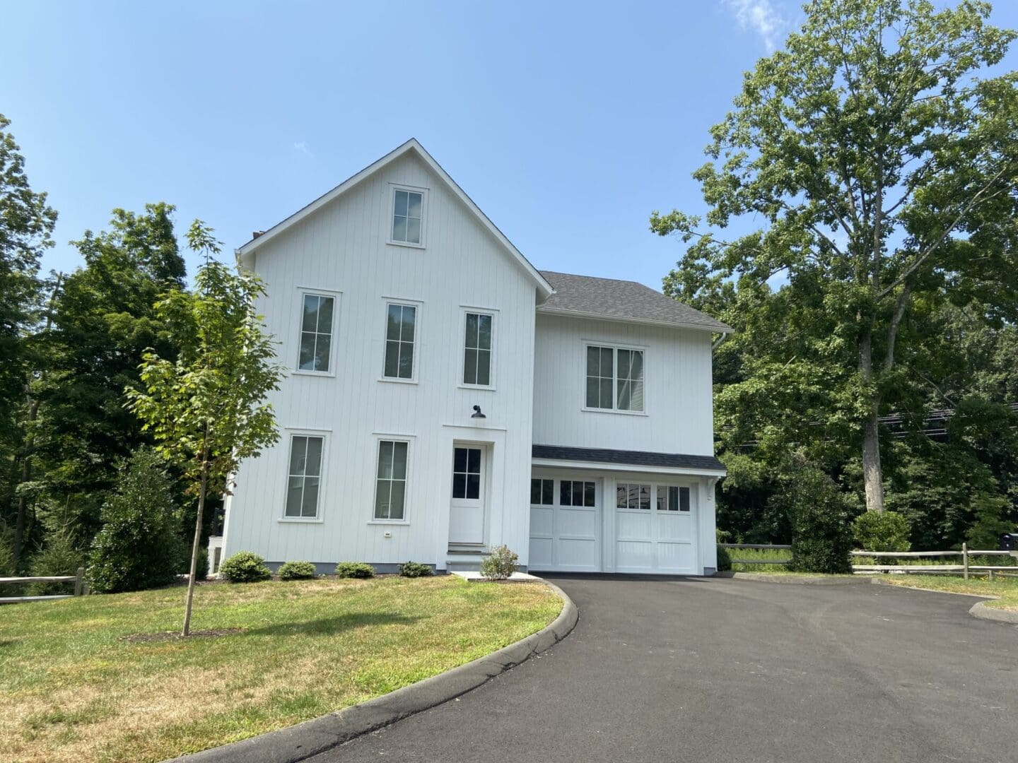 White house with driveway and trees.