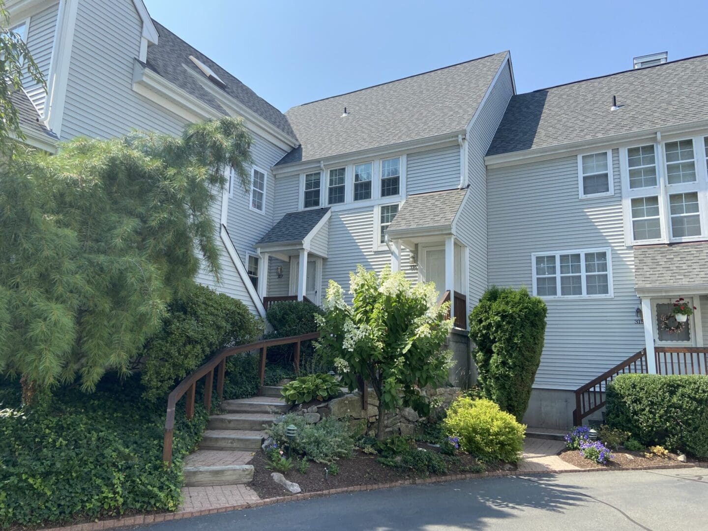 Gray townhouse with a walkway and shrubs.