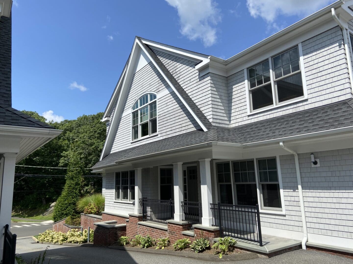 Gray shingled house with porch and windows.