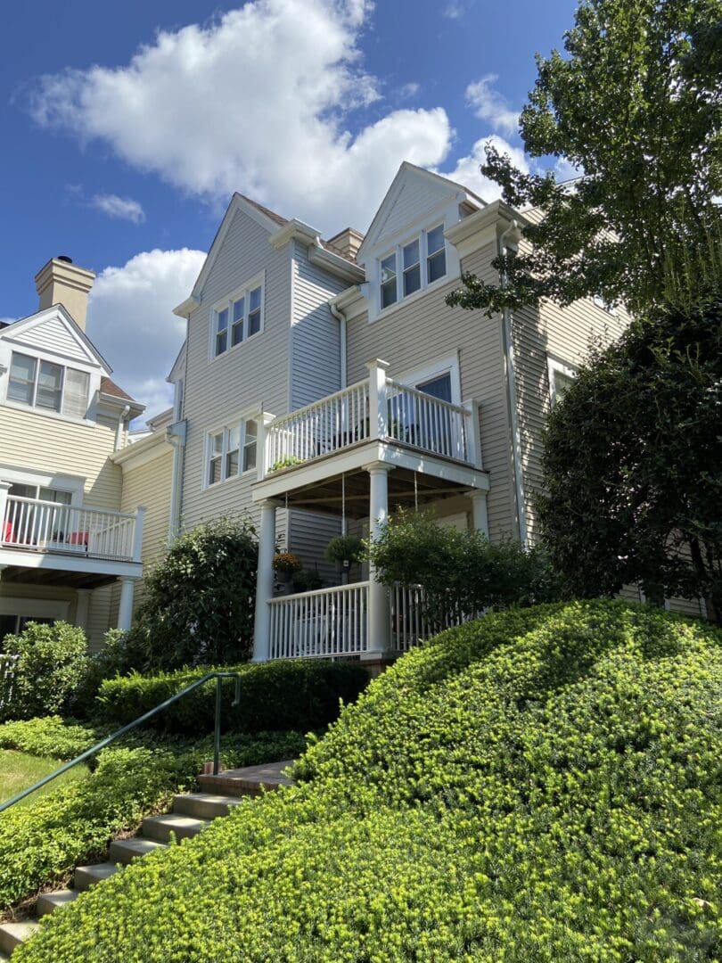 White house with porch and green bushes.