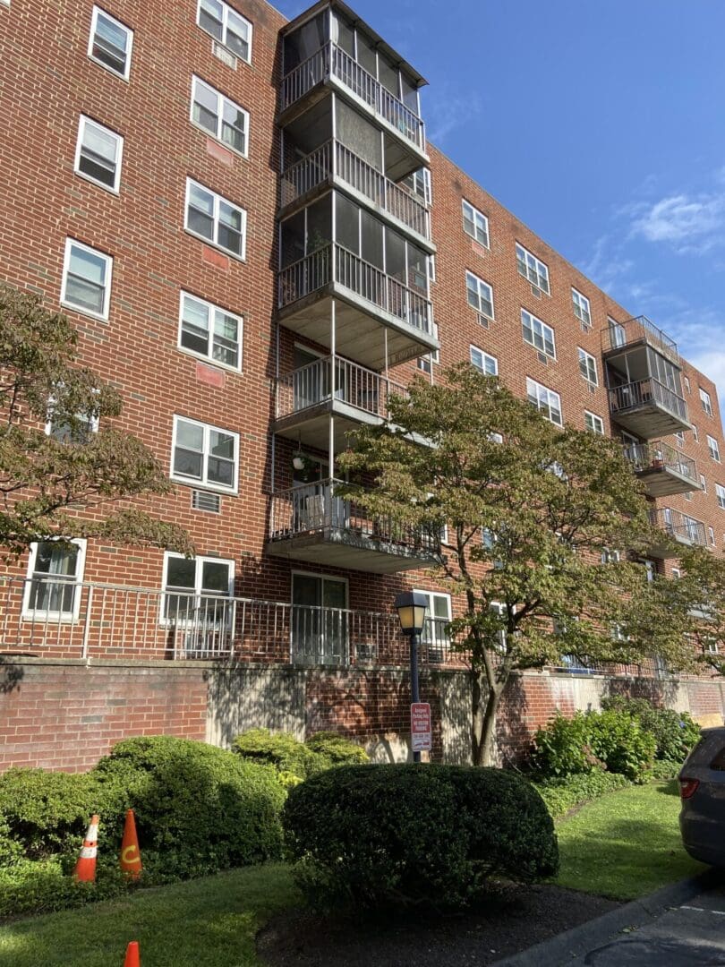 Brick apartment building with balconies and trees.