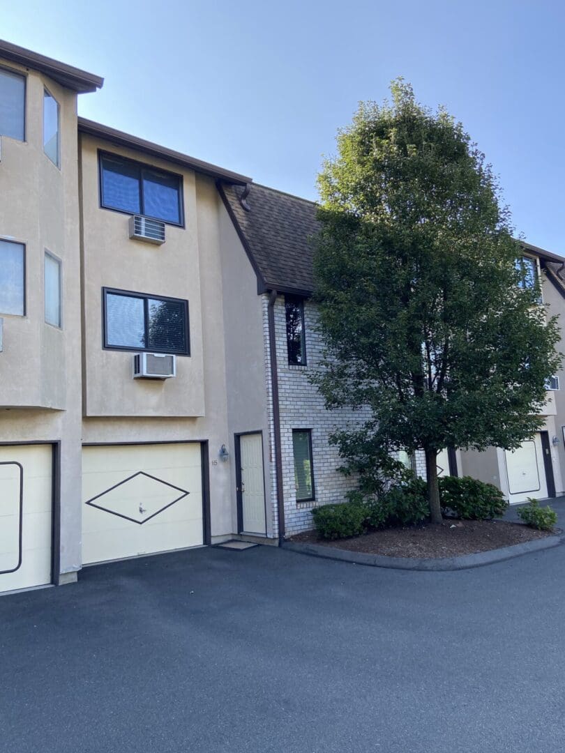 Two-story townhouse with garage and tree.