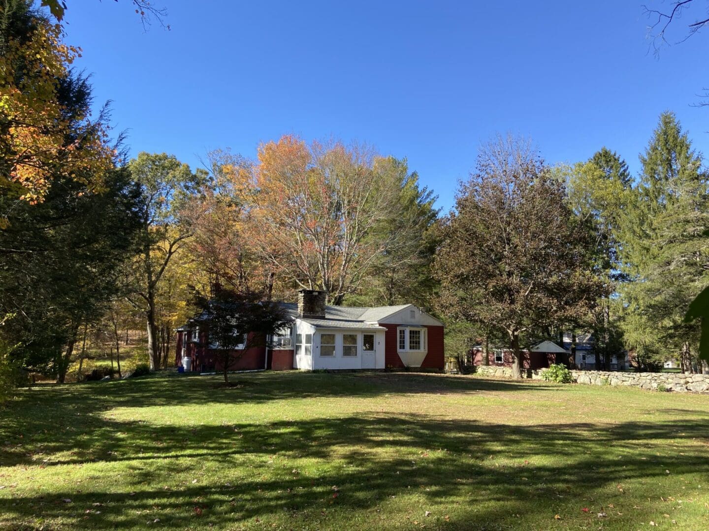 White house with red trim in fall foliage.