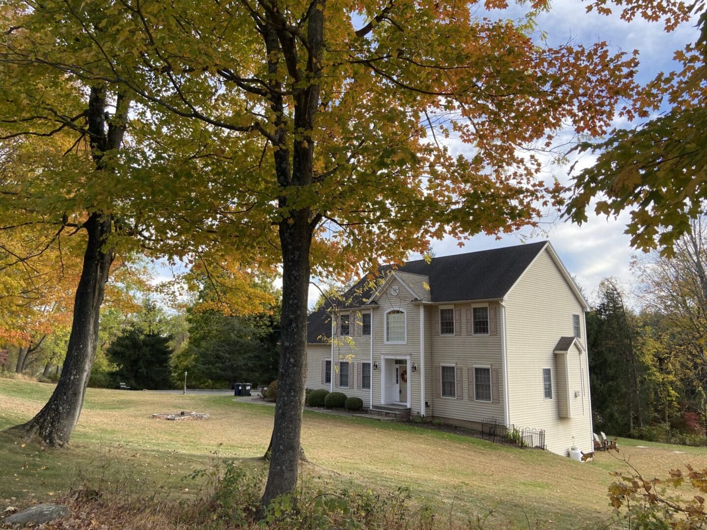 Autumn leaves frame a beige house.