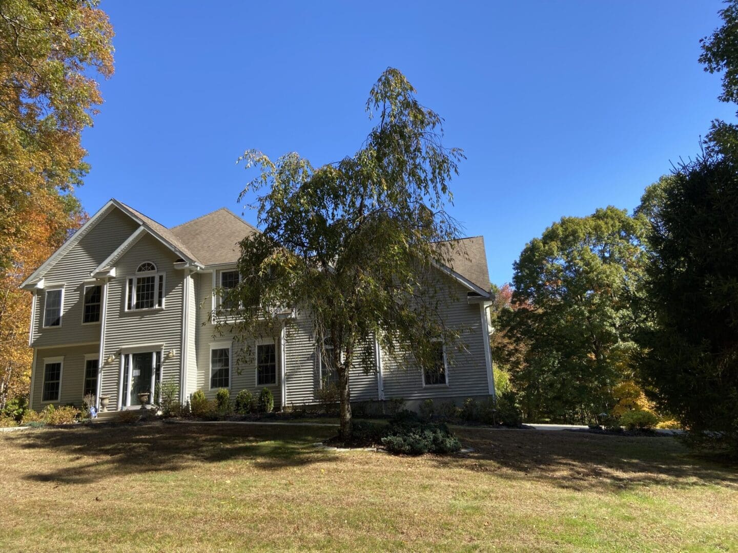 Two-story house with green lawn and trees.